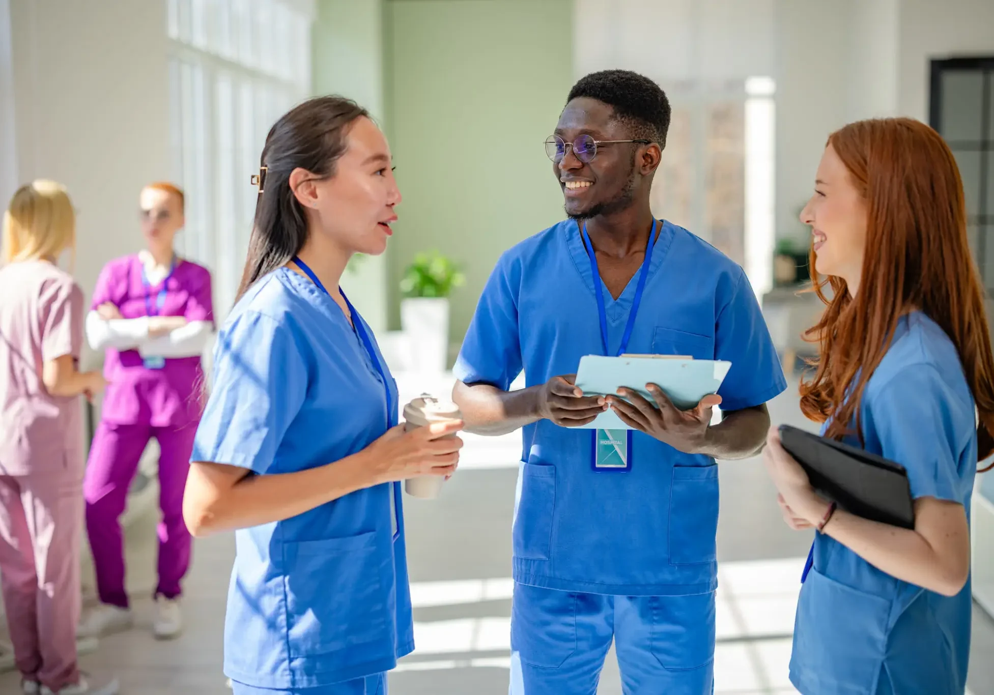 Healthcare professionals discussing patient charts in a hospital corridor.